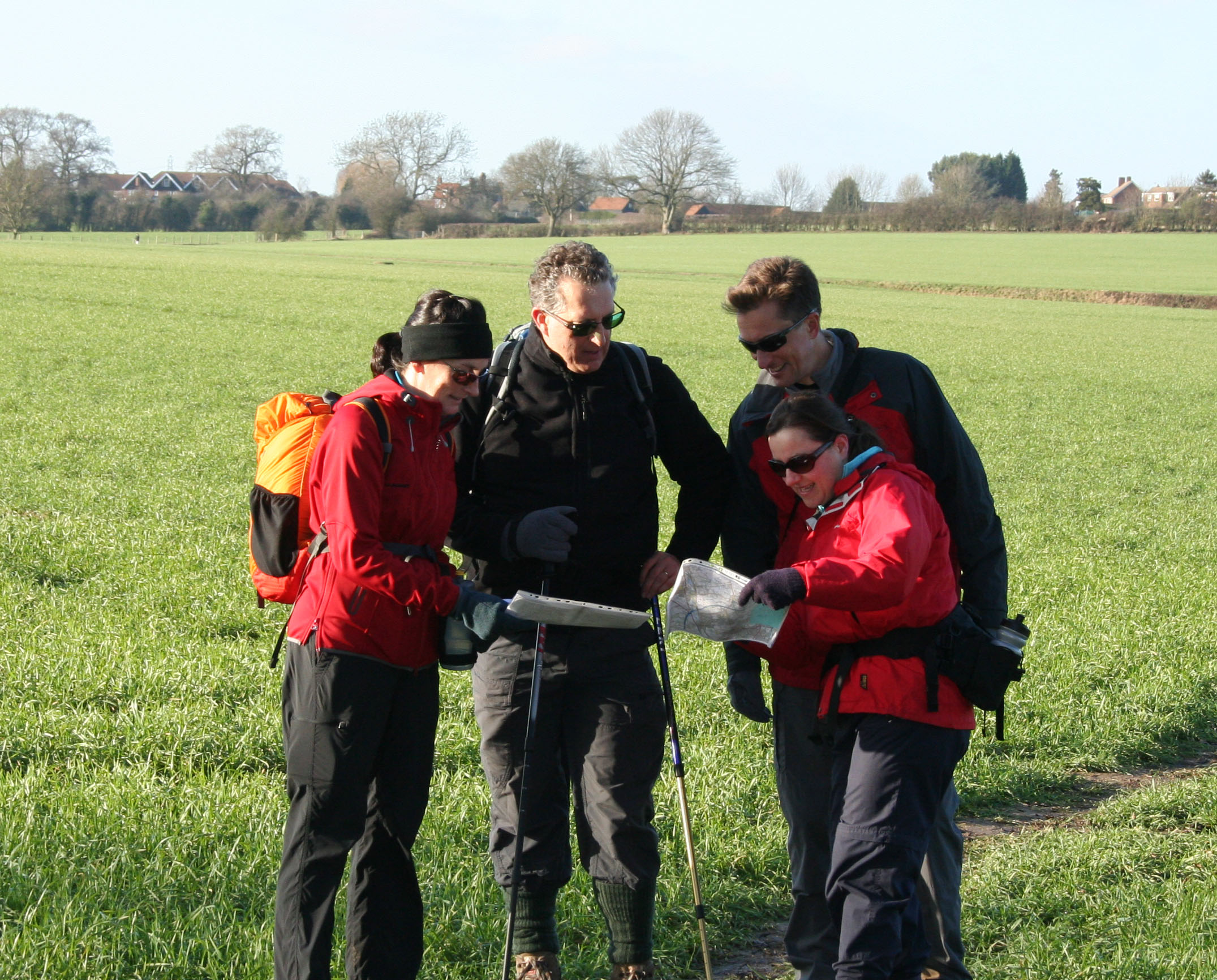 a group of walkers pausing in a green landscape to look at their maps