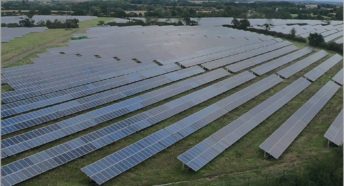 many rows of photovoltaic solar panels covering a large expanse of countryside