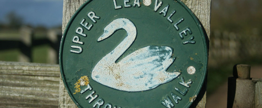 a signpost with the old style Lea Valley waymark, showing a white swan on a dark green background