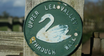 a signpost with the old style Lea Valley waymark, showing a white swan on a dark green background