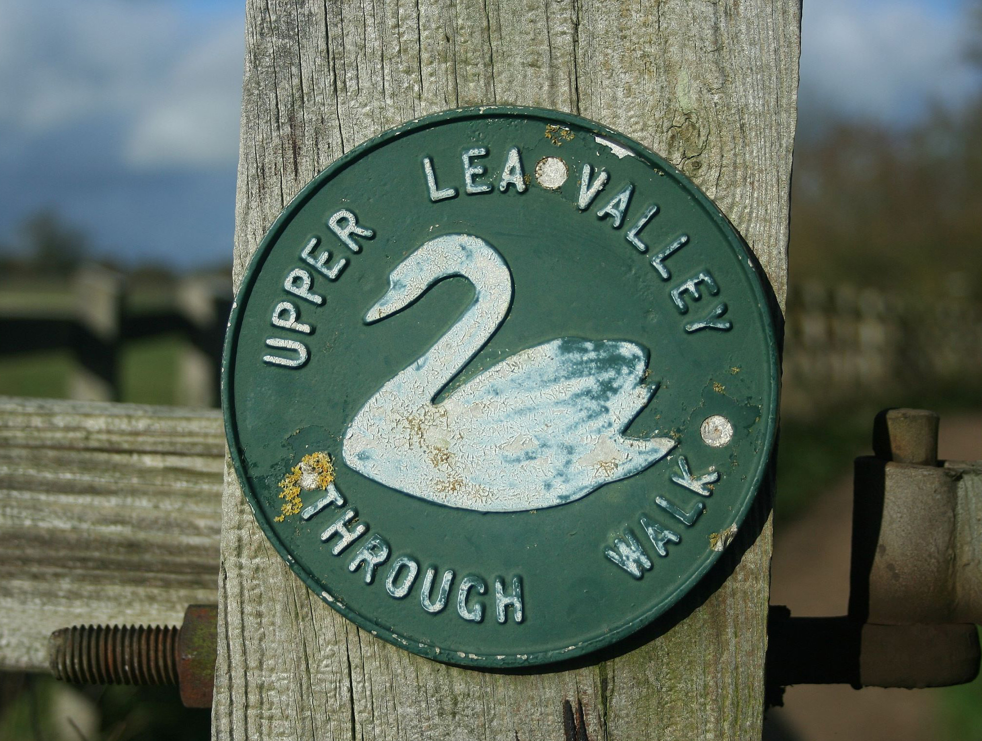 a signpost with the old style Lea Valley waymark, showing a white swan on a dark green background