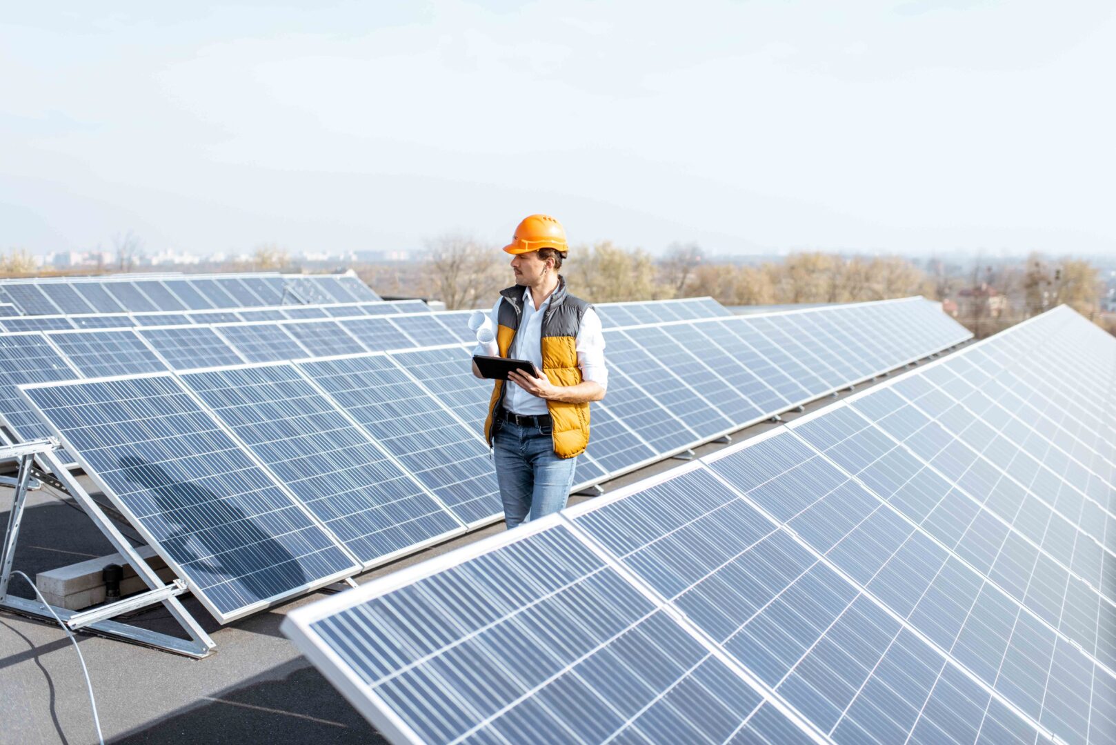 man walking on industrial rooftop and inspecting rows of solar panels