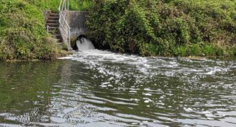foamy water flowing out of a pipe from sewage treatment works into a canal
