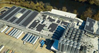 aerial view of blue solar photovoltaic array mounted on rooftop of large industrial building