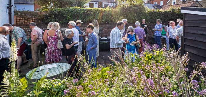 a group of people enjoying a garden party on a sunny summer evening