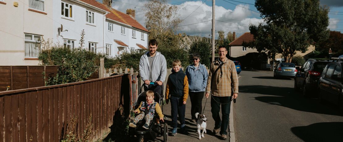 a family walking past affordable housing in a village