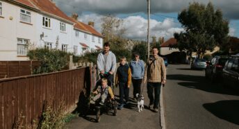 a family walking past affordable housing in a village