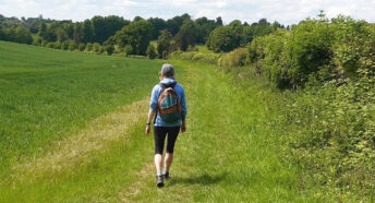 woman walking in the sunshine along grassy path