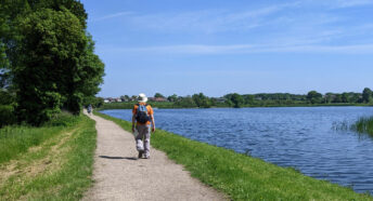 man walking on footpath alongside attractive body of water on a sunny day
