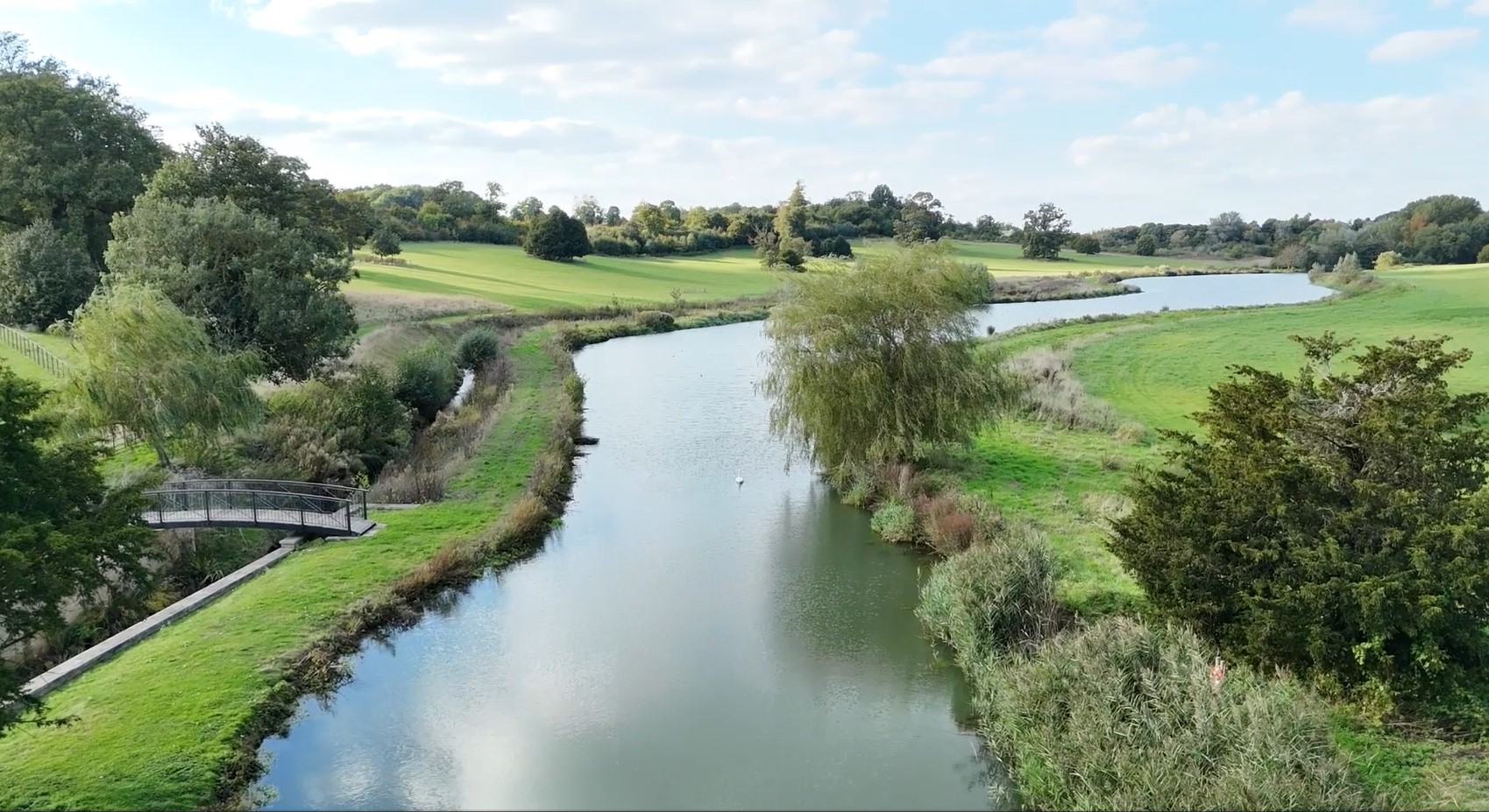 a river surrounded by lush green fields and woodlands