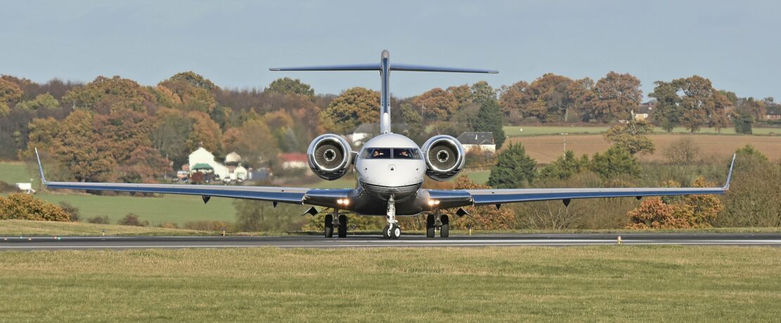 private jet prior to take off at luton airport, green countryside and woodland in the background