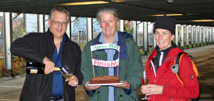 three tired but smiling walkers with cake and champagne