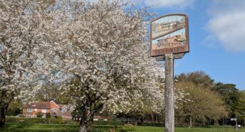 village sign and trees in blossom
