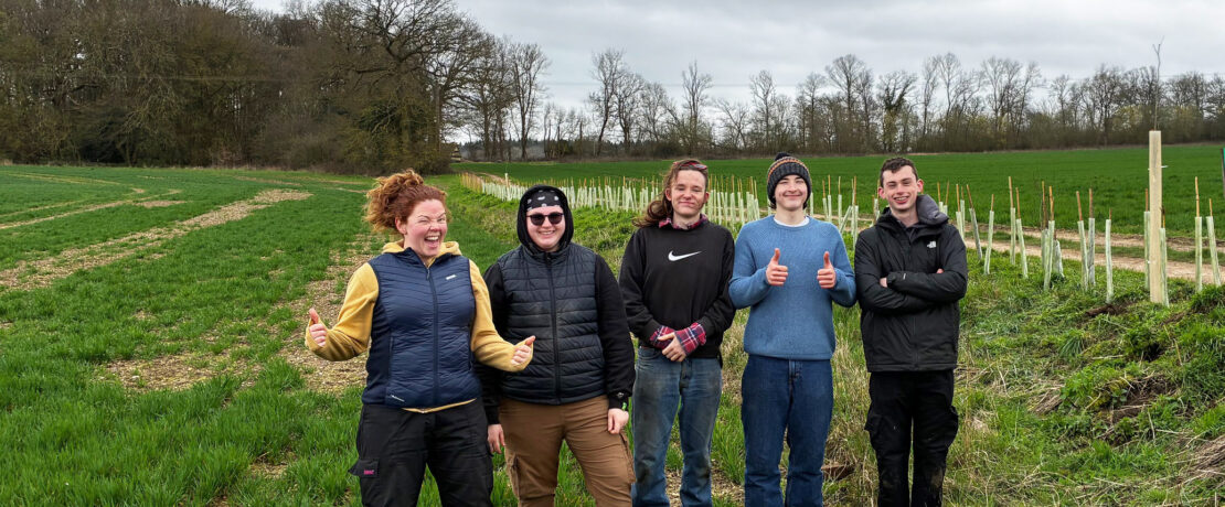 five young people with the hedgerow that they have just finished planting