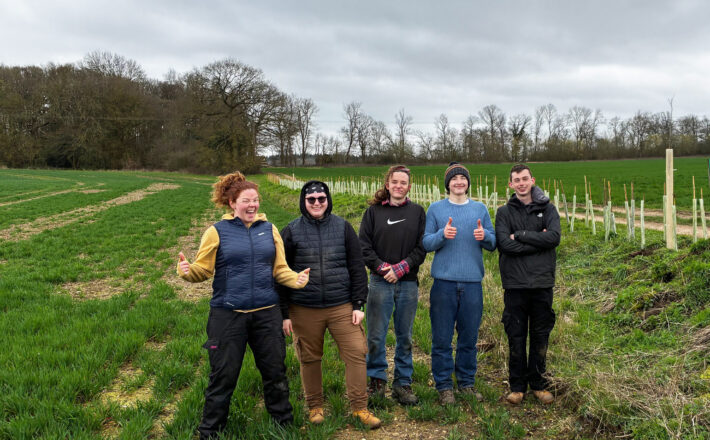 five young people with the hedgerow that they have just finished planting