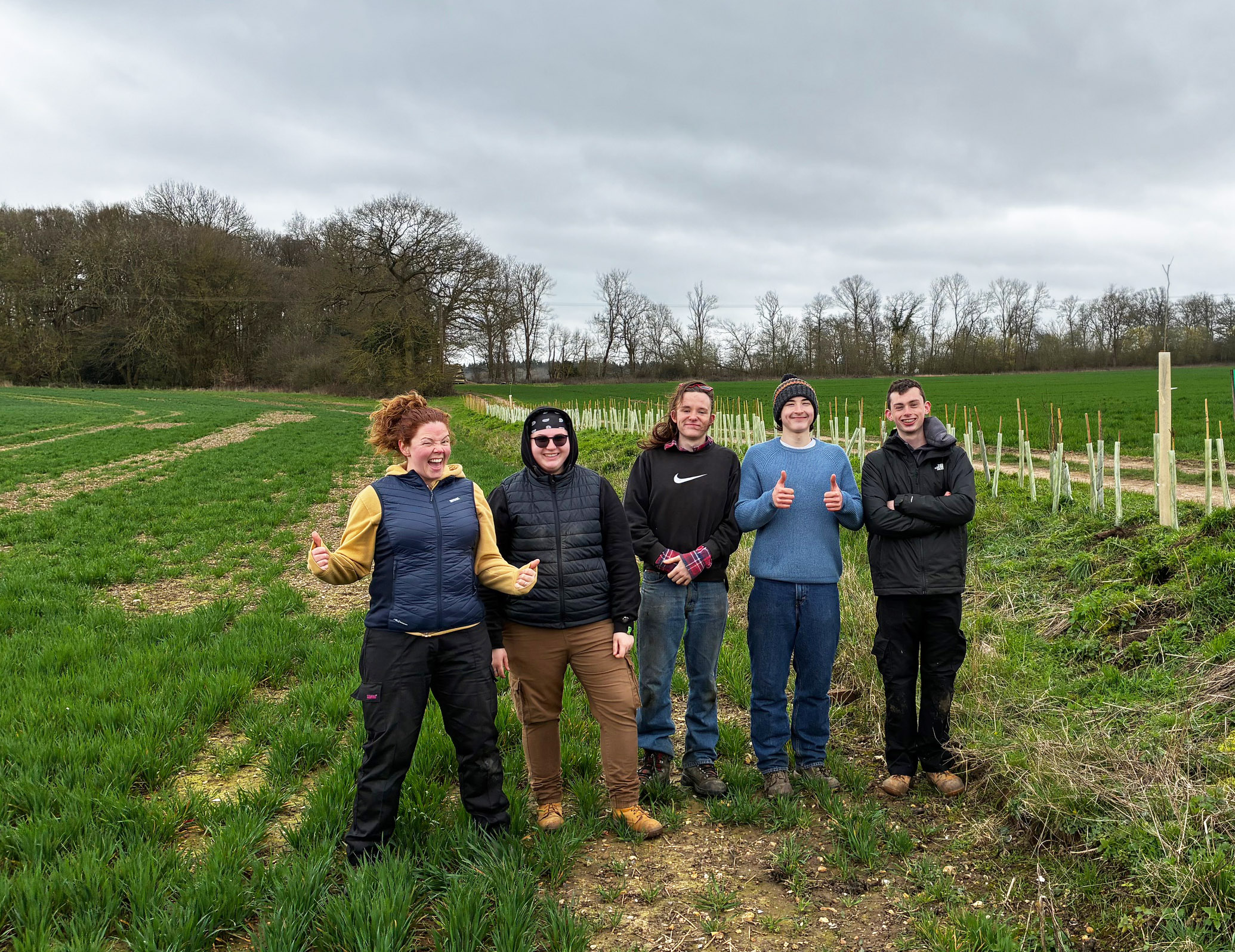 five young people with the hedgerow that they have just finished planting