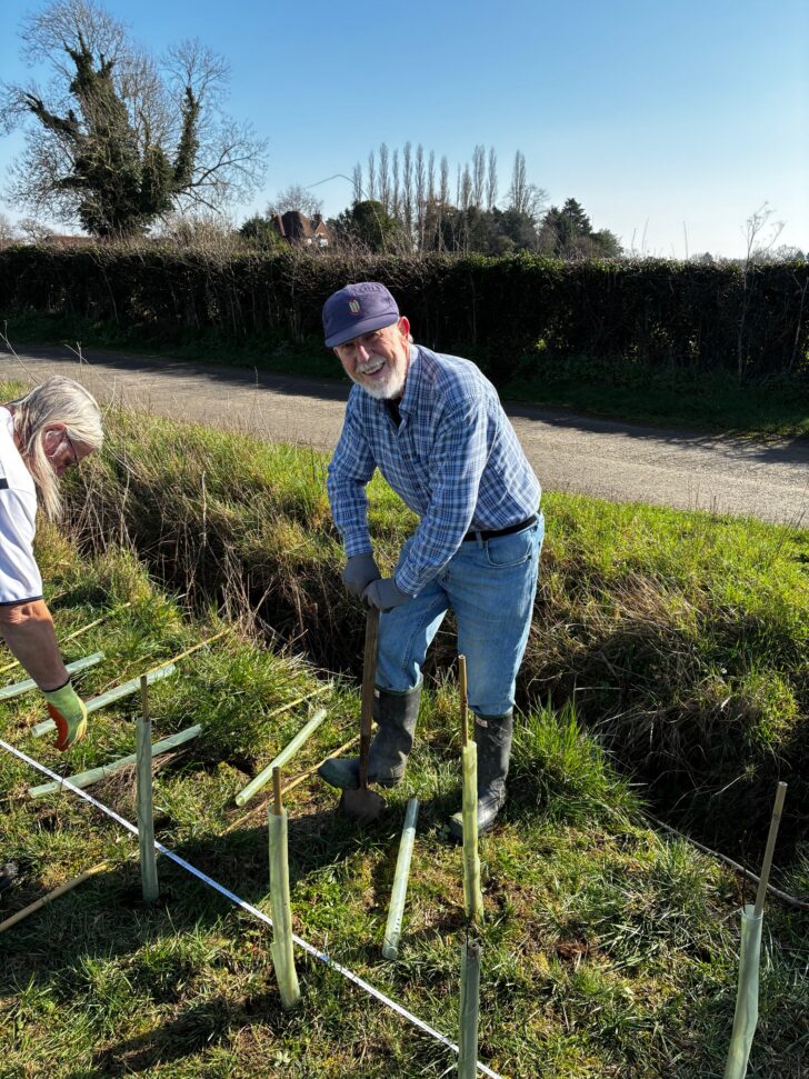 smiling man helping to plant a new hedgerow